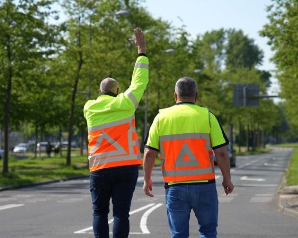 Twee verkeersregelaars, op de rug gezien en staand op een kruispunt