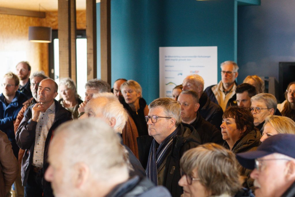 Het publiek luistert naar een presentatie van Silvia Mosterd over de nieuwe Lauwersmeerdijk en de koppelprojecten (waar de getijdenduiker er een van is) in het dijkinformatiecentrum in Lauwersoog.