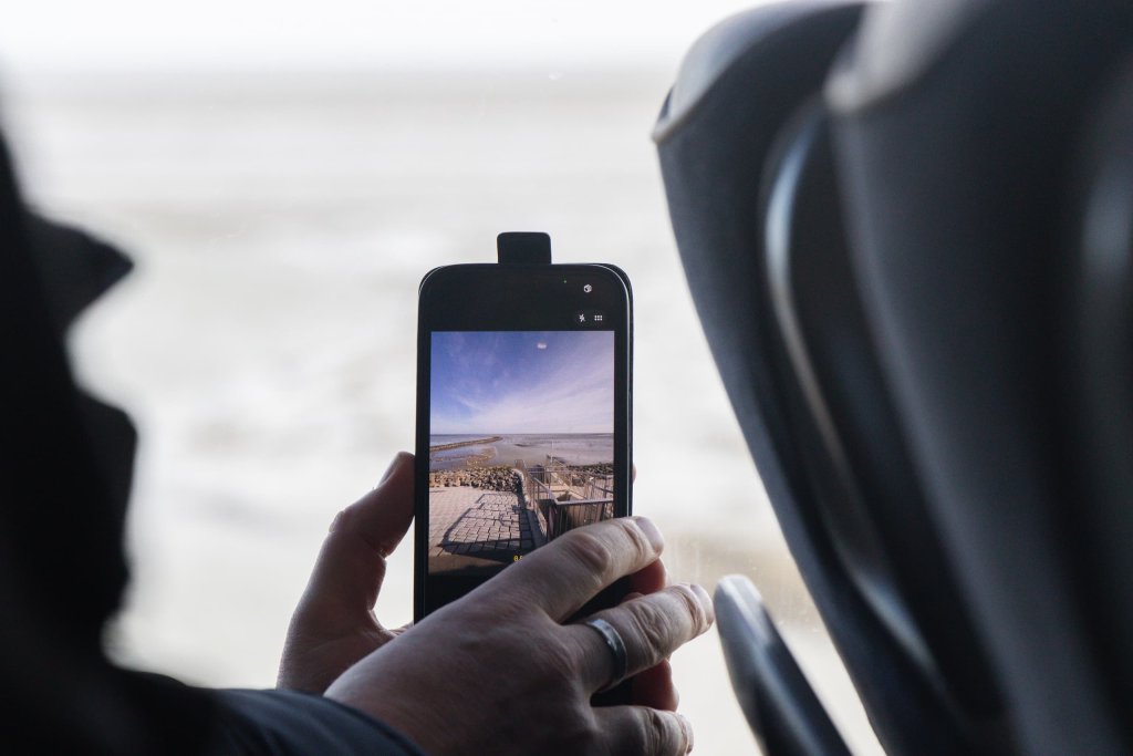 Een deelnemer van de expeditie naar de getijdenduiker maakt tijdens de bustour en foto van de getijdenduiker die uitmondt in de zee aan de buitenzijde van de dijk.