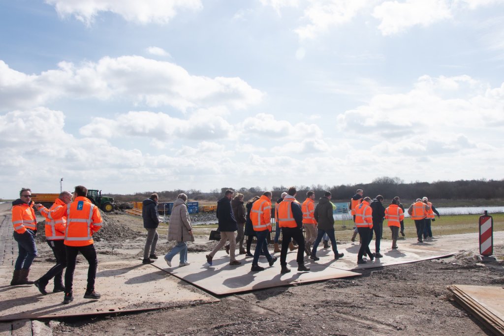 Remco Renting van Provincie Groningen legt, op locatie bij de getijdenduiker achter de bouwhekken aan de binnenzijde op de nieuwe Lauwersmeerdijk, aan het publiek uit waarom Provincie Groningen het initiatief heeft genomen voor de getijdenduiker en hoe hij werkt. 