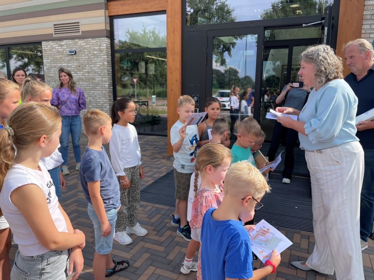 Wethouder Mathijssen deelt flyers uit bij het kindcentrum Heijer
