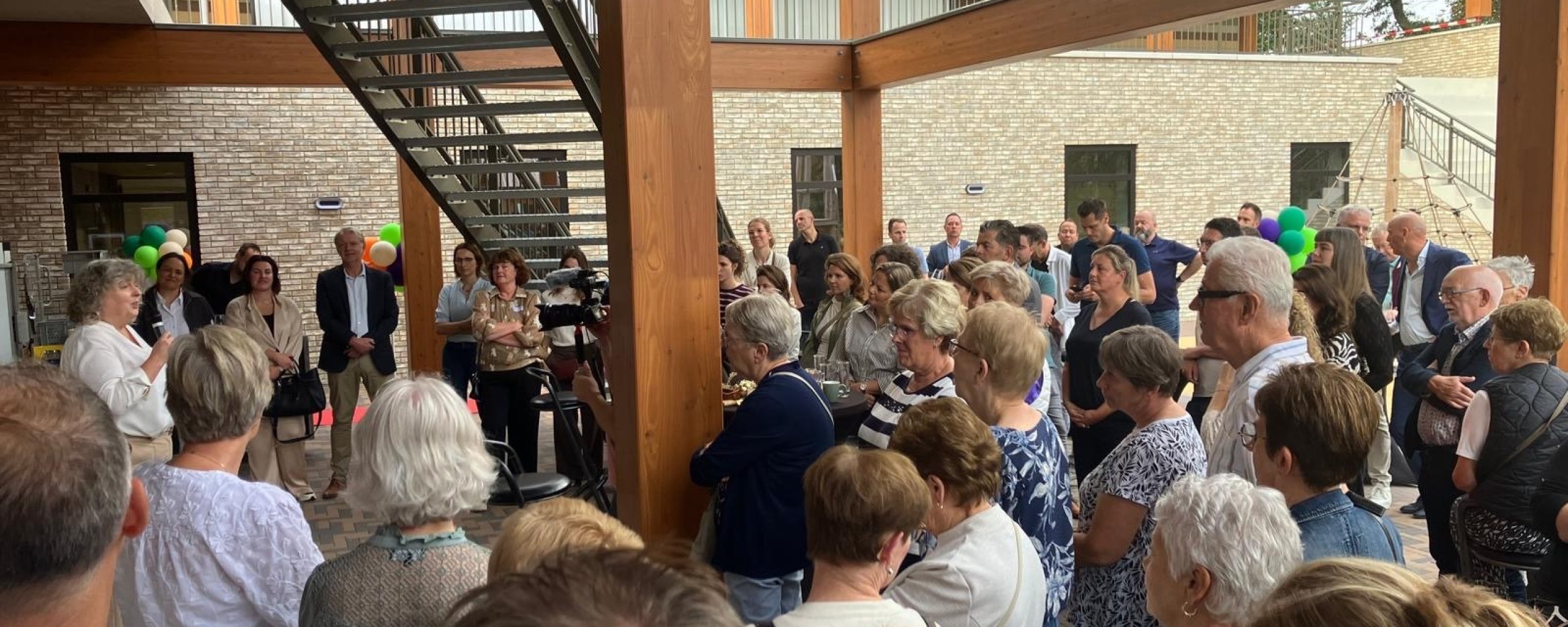 Mensen bij opening kindcentrum, wethouder spreekt