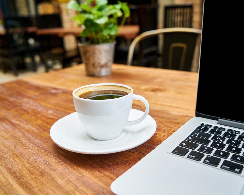 Laptop op een tafel met een kop koffie links naast de laptop