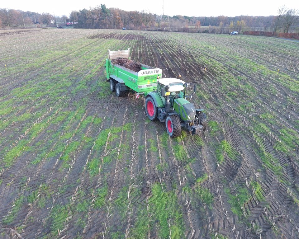 Foto van loonwerker die bladmateriaal verspreid op onderzoeksveld.