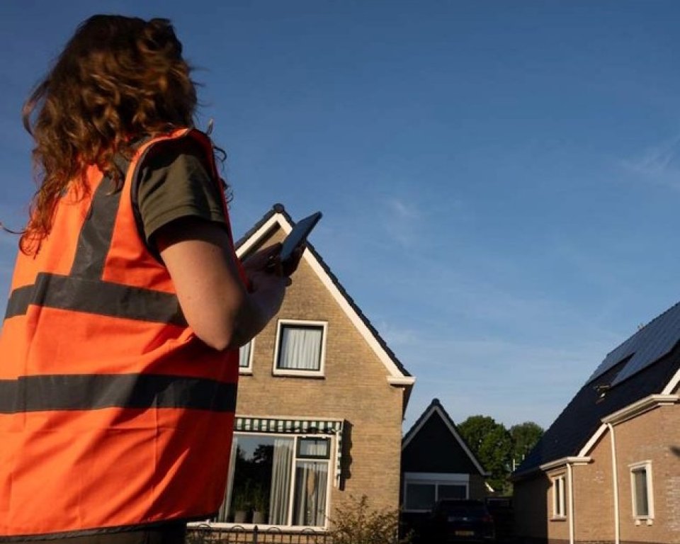 Onderzoeker in woonwijk met oranje hesje aan