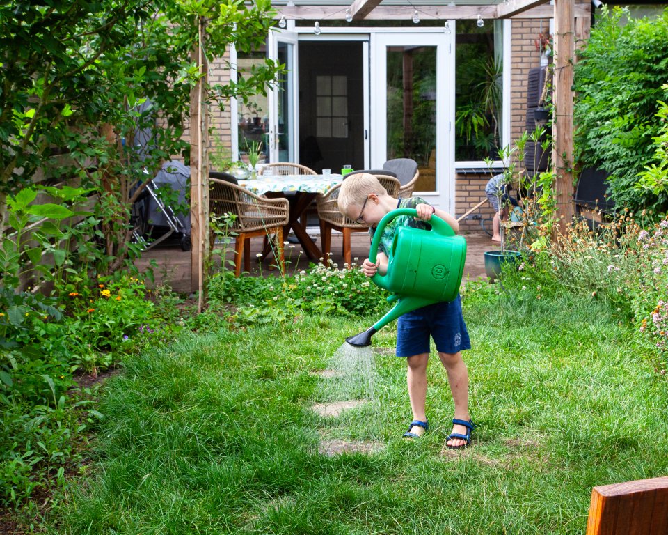 Foto van een kind met een gieter die de de tuin water geeft. Foto ter illustratie.