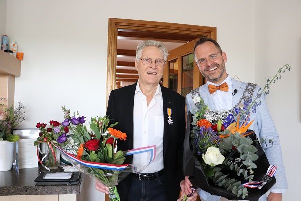 Gedecoreerde de heer Strien met bloemen, tompoezen en burgemeester Laurens de Graaf