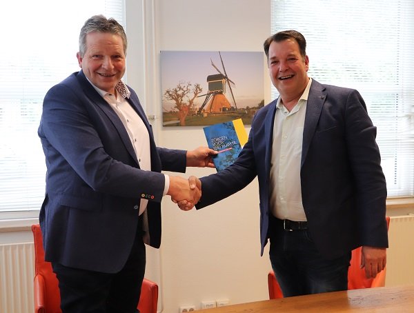 Fractievoorzitters De Leede en Strien tonen het bestuursakkoord en schudden elkaar binnen de hand. Op de achtergrond een schilderij van de Cabauwse molen.