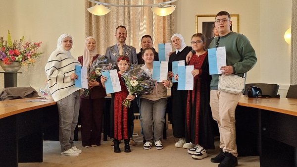 De acht inwoners aan wie het Nederlanderschap is verleend met burgemeester Laurens de Graaf in de raadzaal van het gemeentehuis