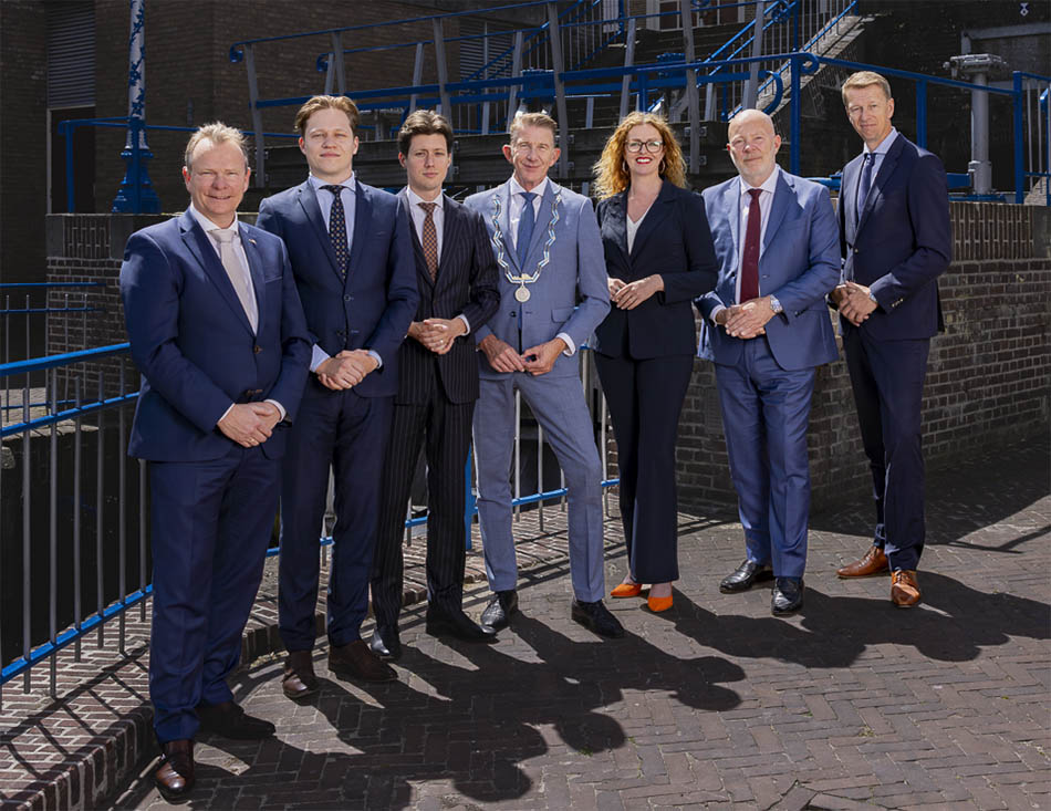 Foto van het college van B en W, samen met de gemeentesecretaris, bij de Monstersche Sluis