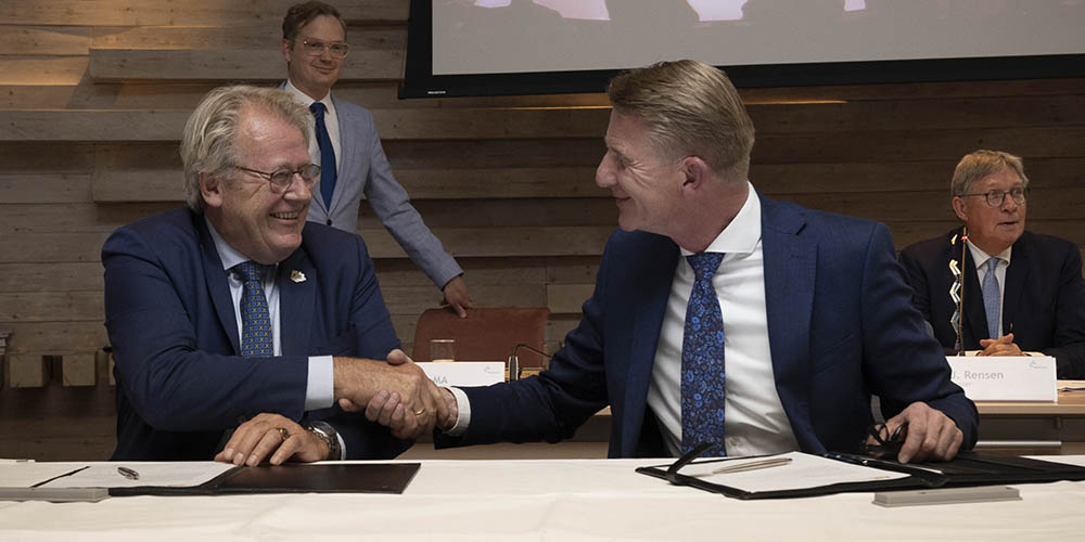 Foto van Commissaris van de Koning Jaap Smit die burgemeester Jack de Vries de hand schudt.