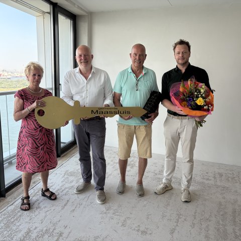 Wethouder Robert Simons met de nieuwe bewoners van de laatste woning in Het Baken tijdens de sleuteloverdracht. Met deze oplevering is de ontwikkeling van Het Balkon van Maassluis aan de Nieuwe Waterweg afgerond.