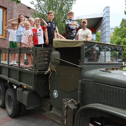 Foto van enkele kinderen die poseren in een militair voertuig