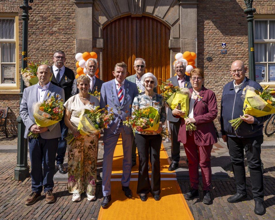 De gedecoreerden van de Lintjesregen 2026 samen met burgemeester Jack de Vries voor de Groote Kerk. Twee decorandi waren vandaag niet aanwezig.