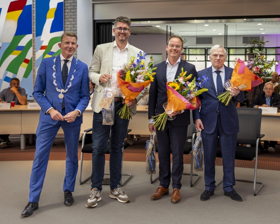 De afbeelding toont Burgemeester Jack de Vries samen met de drie vertrekkende wethouders Martijn Kroonen, Sjoerd Kuiper en Sjef Evers tijdens het afscheid in de gemeenteraad van 16 juni.