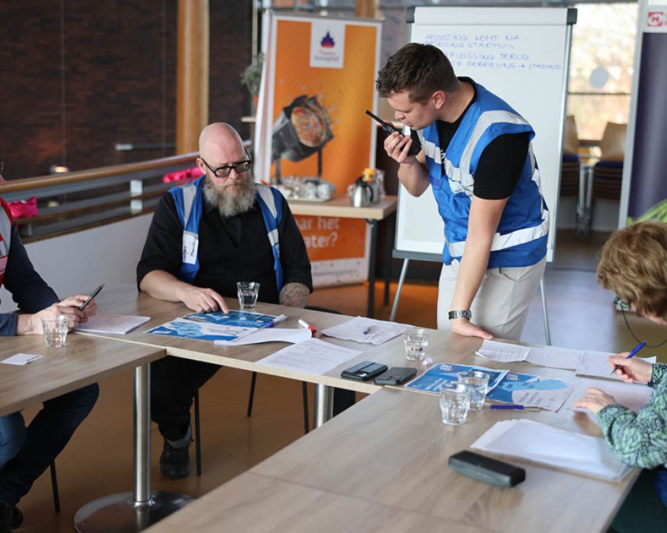 Foto van deelnemers aan de oefening die informatie uitwisselen en besluiten nemen zonder reguliere stroom- en dataverbindingen