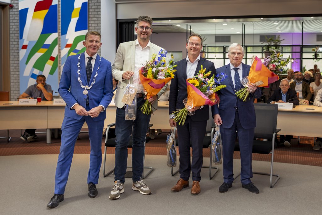 De afbeelding toont Burgemeester Jack de Vries samen met de drie vertrekkende wethouders Martijn Kroonen, Sjoerd Kuiper en Sjef Evers tijdens het afscheid in de gemeenteraad van 16 juni.