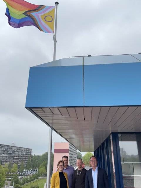 De vertegenwoordigers van het Regenboogplatform en Sjoerd Kuiper onder de regenboogvlag