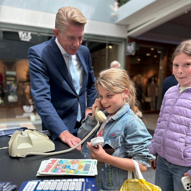 Burgemeester De Vries en twee kinderen met de fraudefoon bij de politiestand
