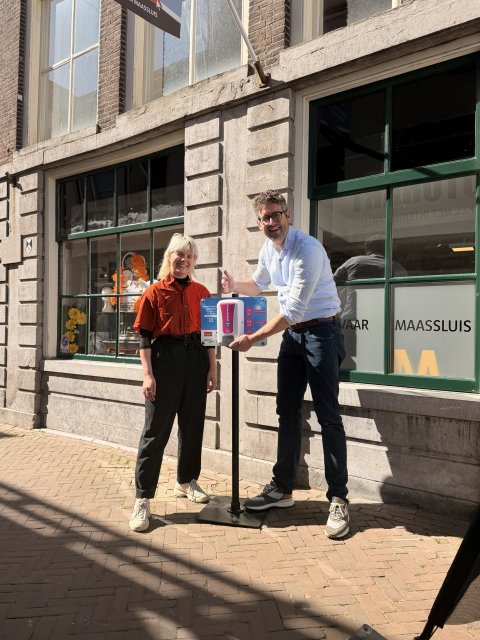 Foto van wethouder Kroonen die toont hoe de zonnebrandpomp te gebruiken