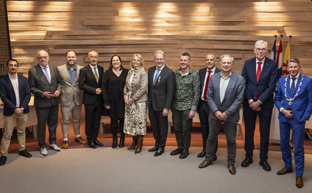 Foto van de elf afscheidnemende gemeenteraadsleden samen met burgemeester De Vries tijdens de bijzondere raadsvergadering op 31 maart 2026