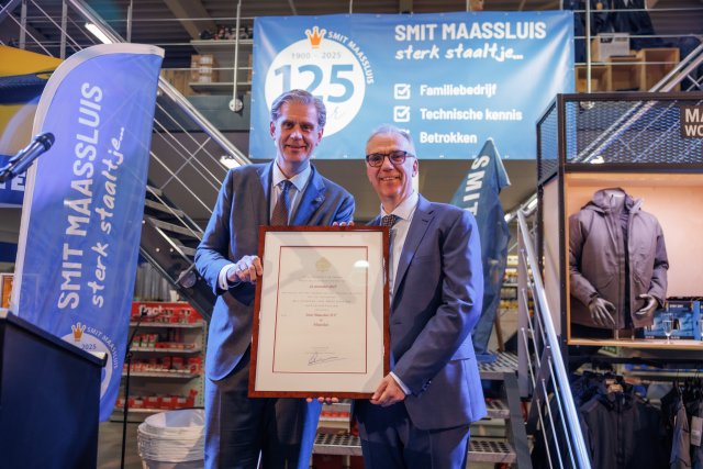 De foto toont dat Peter Smit het predicaat Hofleverancier ontvangt uit handen van de Commissaris van de Koning in Zuid-Holland tijdens de viering van het 125-jarig jubileum van Smit Maassluis.