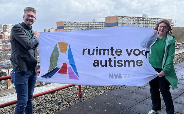 Foto van wethouder Martijn Kroonen en Anouk Breeman van de NVA met de vlag van de Autismeweek.