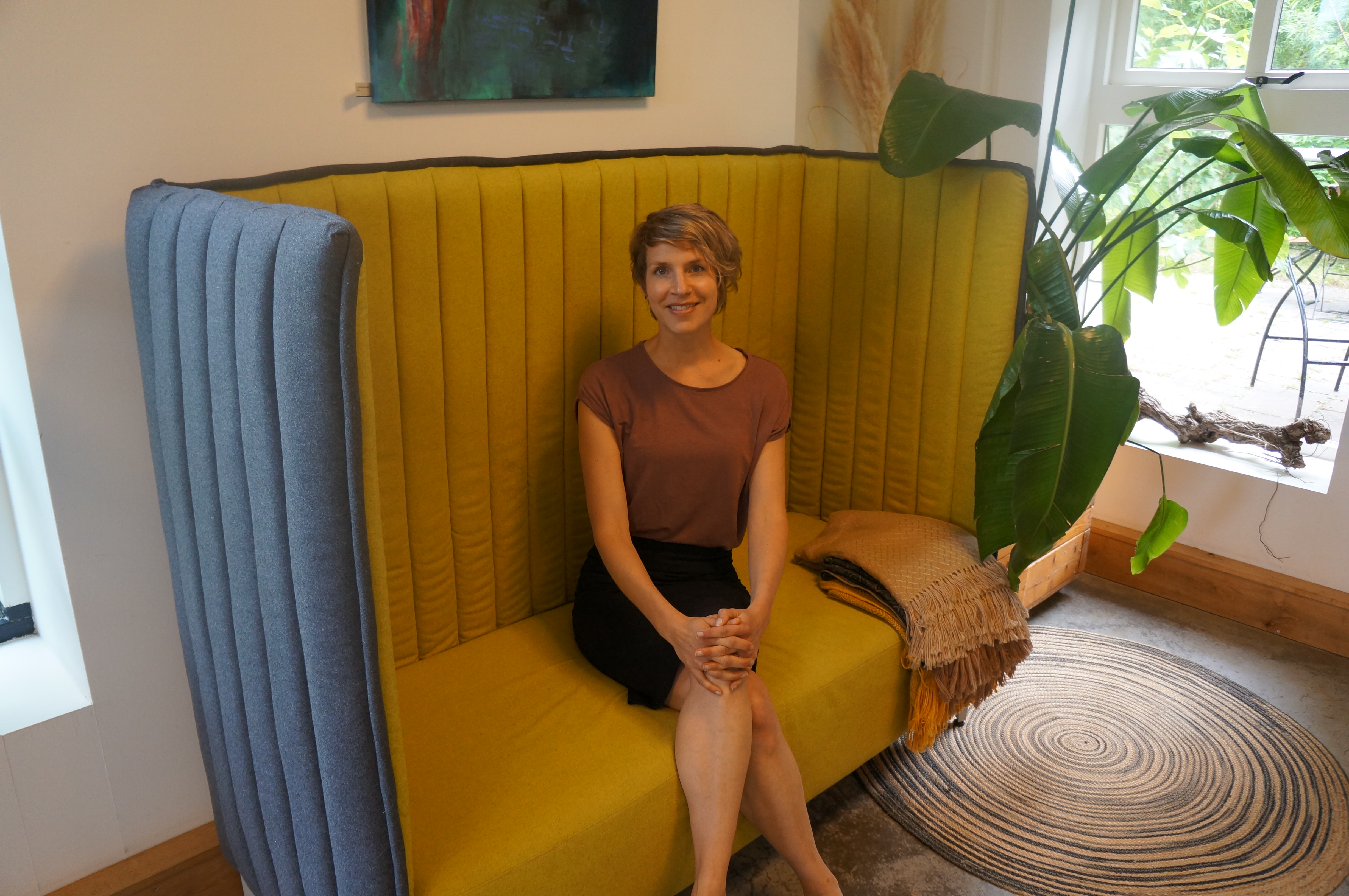 Joyce van Zwet zittend op een gele bank