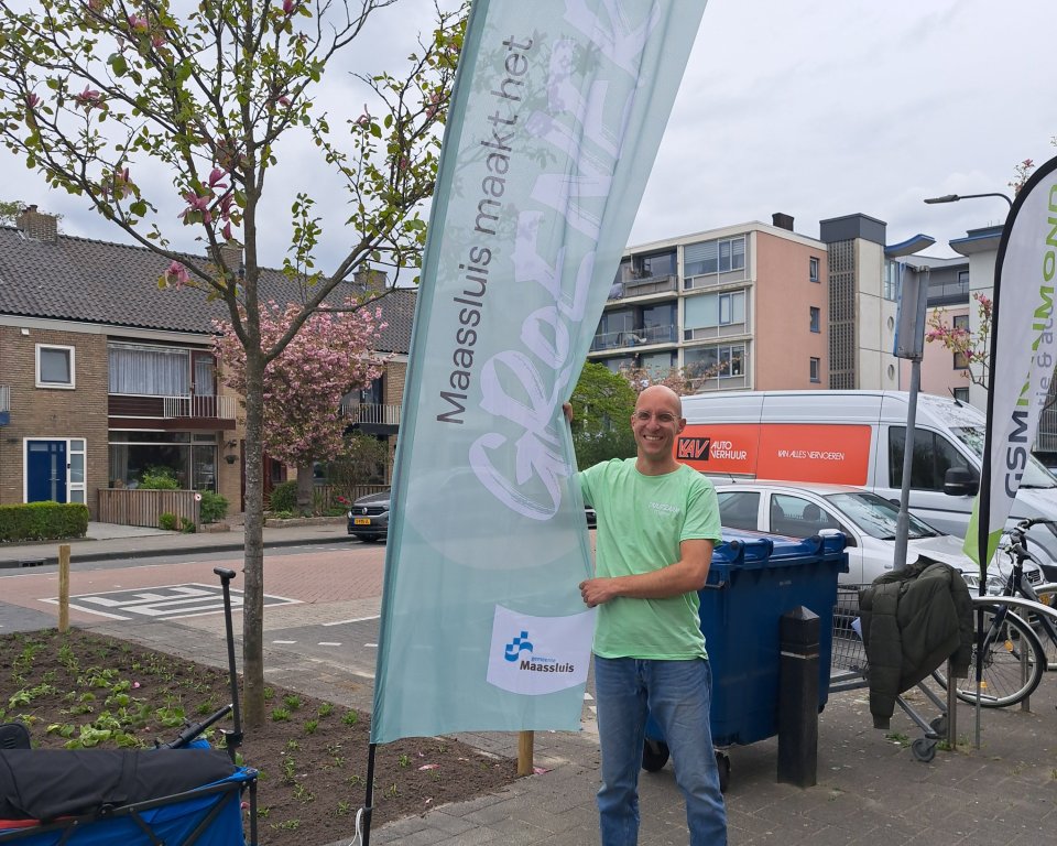 Klimaatburgemeester Patrick Steenks houdt een Maassluis maakt het groener vlag vast