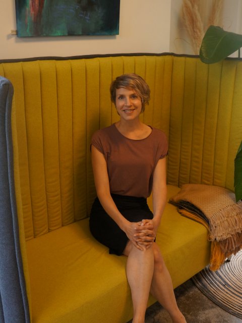 Joyce van Zwet zittend op een gele bank