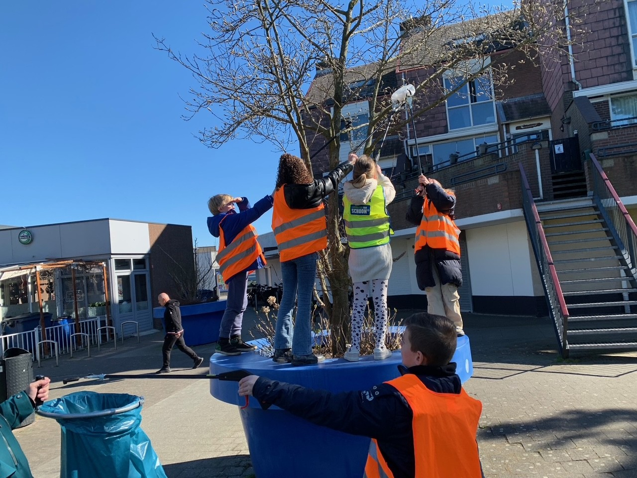 Kinderen halen afval uit een boom