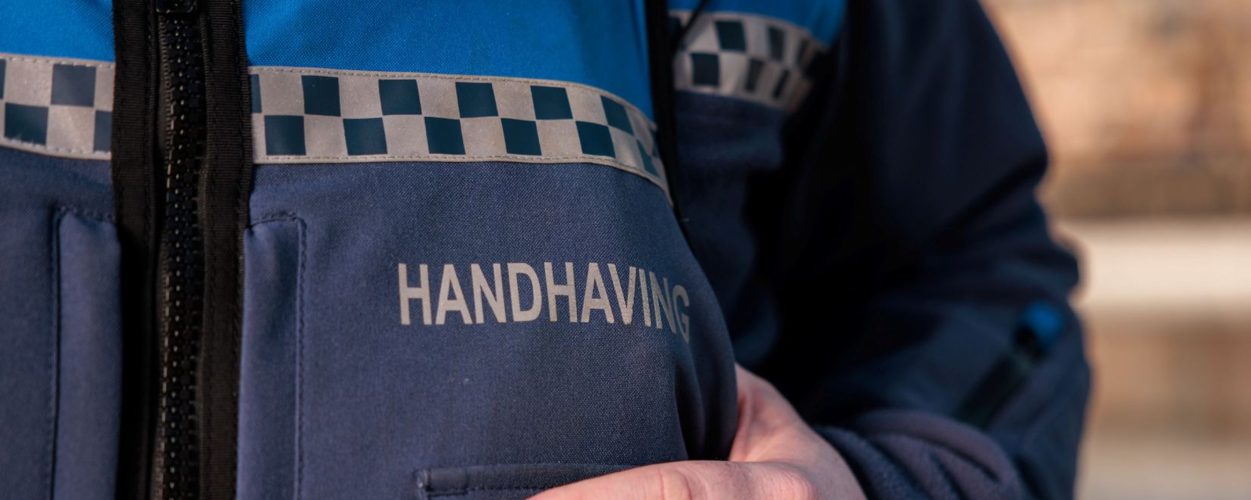 In witte blokletters het woord handhaving op een uniform.