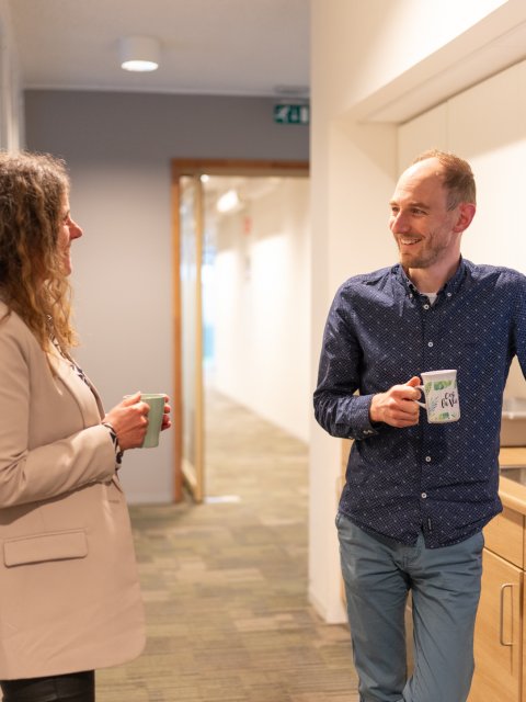 Foto van twee collega's bij het koffieapparaat