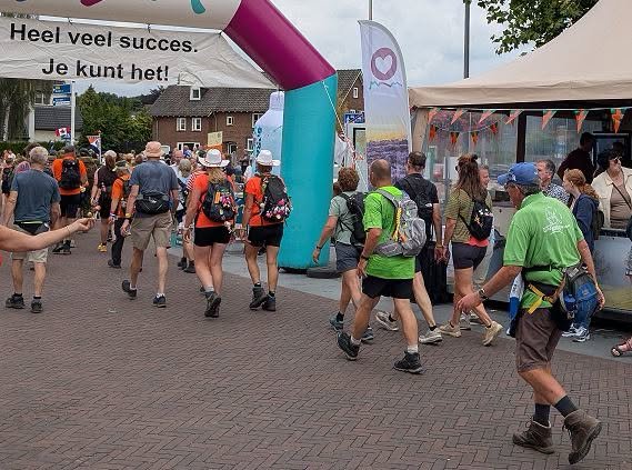 Wandelaars lopen op het Raadhuisplein onder de boog door met de tekst: ‘Heel veel succes. Je kunt het!’
