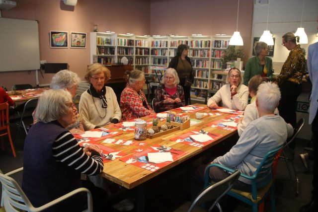Deelnemers aan de vrijheidsmaaltijd in Molenhoek. De burgemeester staat op de achtergrond met een van de deelnemers te praten.