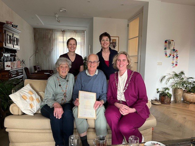 Het bruidspaar en burgemeester van Dijk zitten op de bank en daarachter staan de dochters.