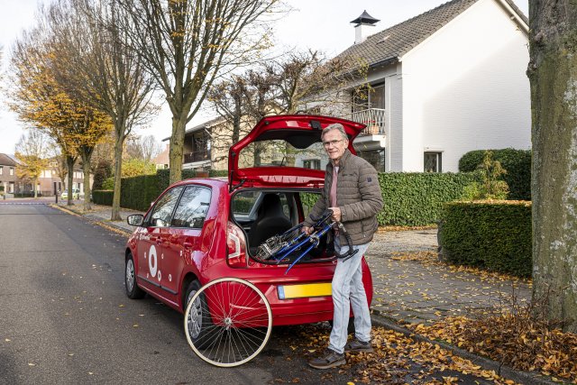 Foto van een man die een gedemonteerde fiets uit een deelauto haalt.