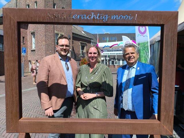 links wethouder Rodoe, midden burgemeester van Dijk en rechts wethouder Herings  voor een frame.