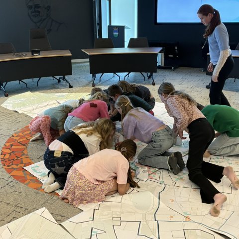 Leden van de kinderraad zoeken hun eigen huis op een grote plattegrond van Nederweert