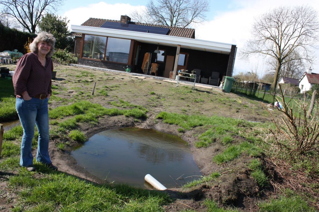 Jane Schlijper bij de wadi in haar achtertuin, met op de achtergrond haar verbouwde bungalow