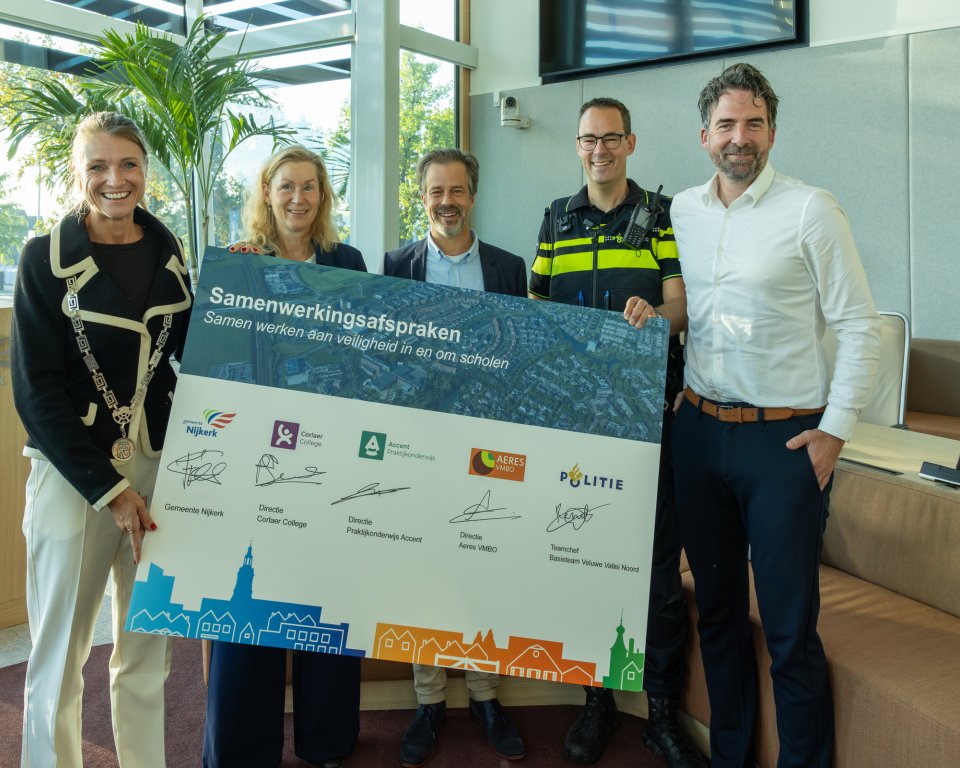 De groep die heeft ondertekent inclusief de burgemeester met het bord dat is ondertekent.