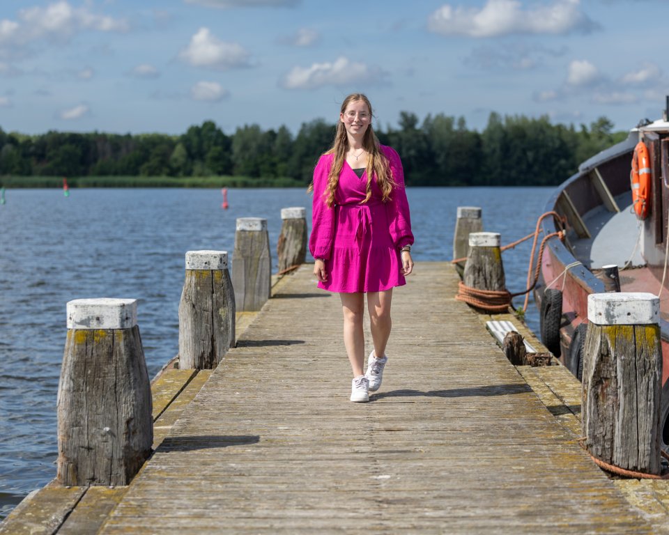 Foto van meisje waar het artikel over gaat. Op een steiger met een boot. 