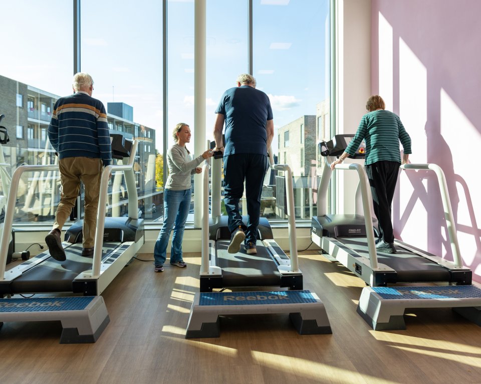 personen op loopband met begeleider in sportzaal