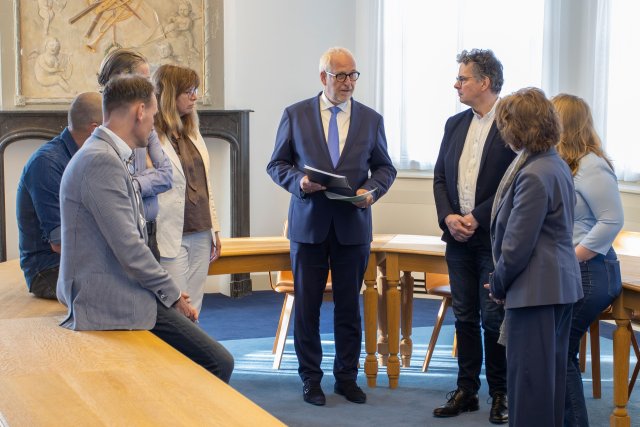 Onderzoeker Anton van Renssen en de begeleidingscommissie in gesprek met burgemeester Gerard Renkema.