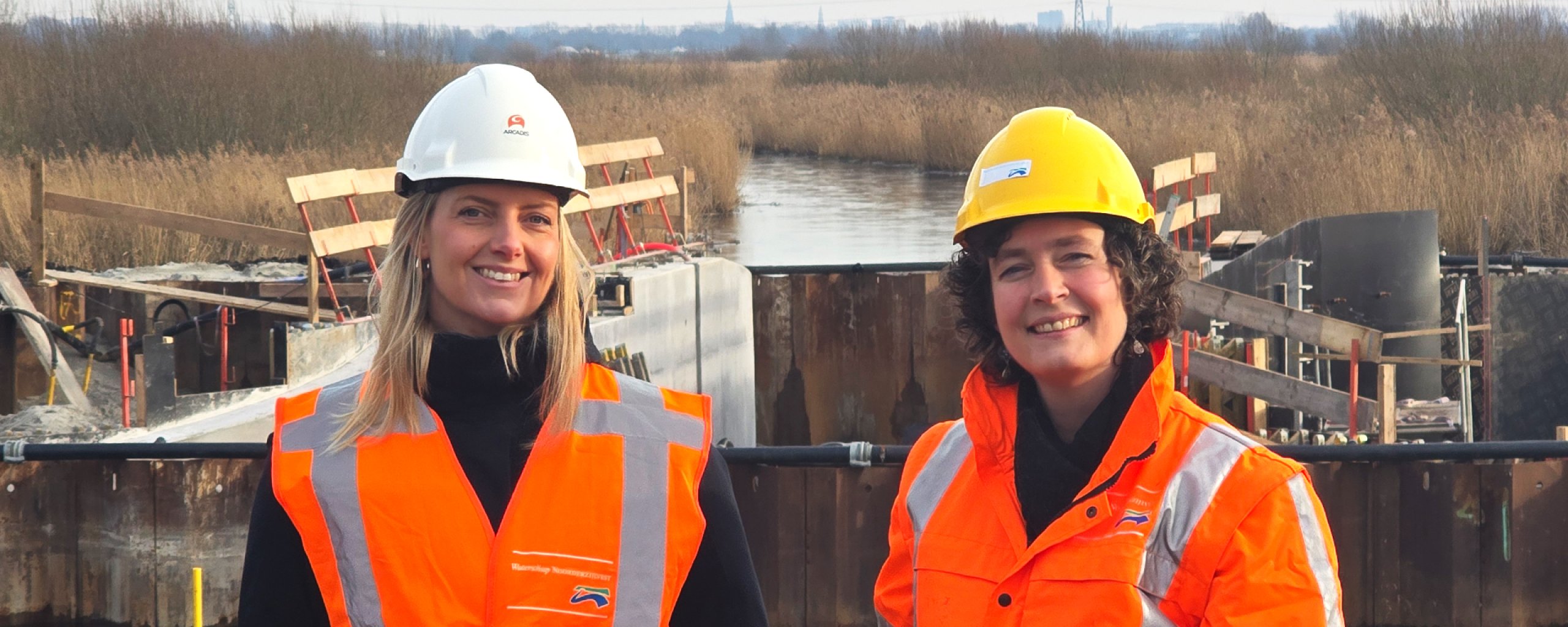 Daniëlle Hjartåker of Arcadis and Marieke van Leeuwen of Noorderzijlvest Water Authority at the Vischlust weir (northern weir) in De Onlanden. The usedd sheet pile wall can be seen in the background.    