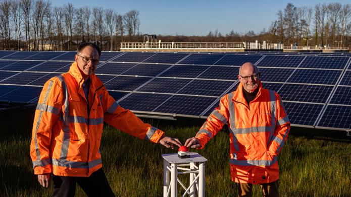 Dagelijks bestuurslid Herman Beerda en adviseur duurzaamheid Tjitse Mollema van waterschap Noorderzijlvest nemen bij de zuiveringsinstallatie in Eelde de zonneparken symbolisch in bedrijf. 