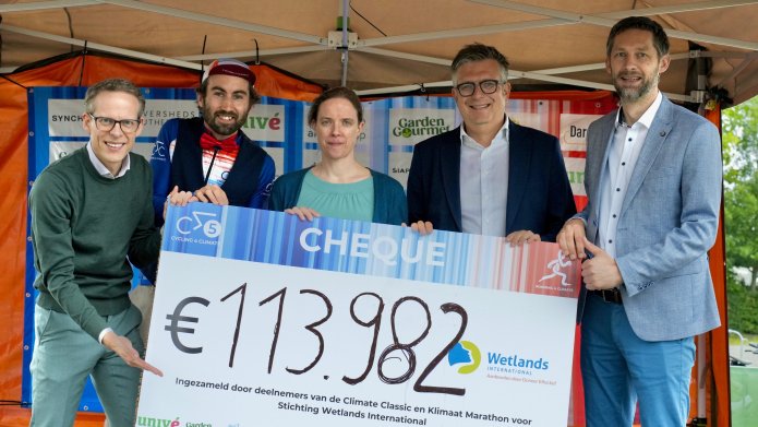 Bestuurders van 5 betrokken organisaties houden een cheque omhoog met daarop het bedrag 113.982 euro