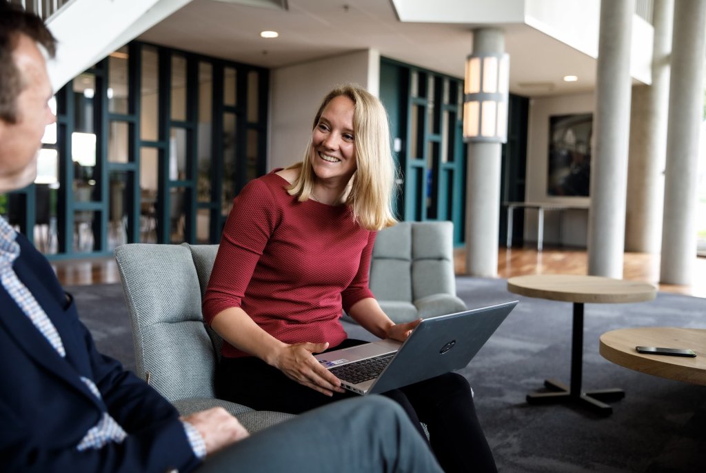 Ester de Boer zit op een bank met haar laptop op schoot in gesprek met een klant