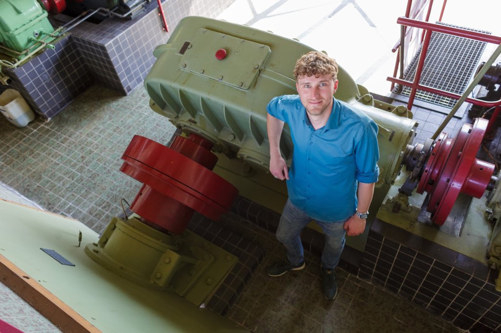 Robin is binnen bij het gemaal H.D. Louwes, en staat geleund tegen een motor van het gemaal