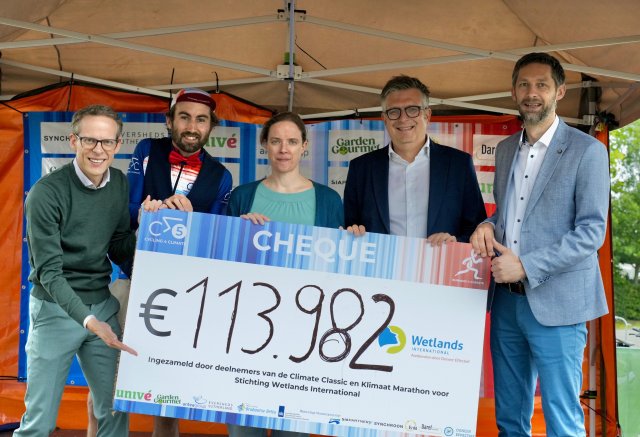 Vijf bestuurders houden een cheque omhoog met daarop het bedrag 113.982 euro